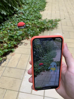 A phone showing an augmented reality character placed on a garden path